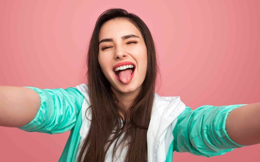 a girl sticking out her tongue while taking selfie