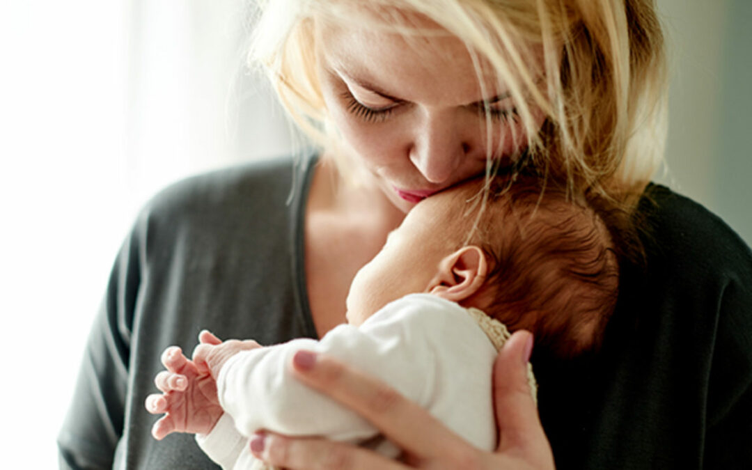 a woman holding and kissing her baby